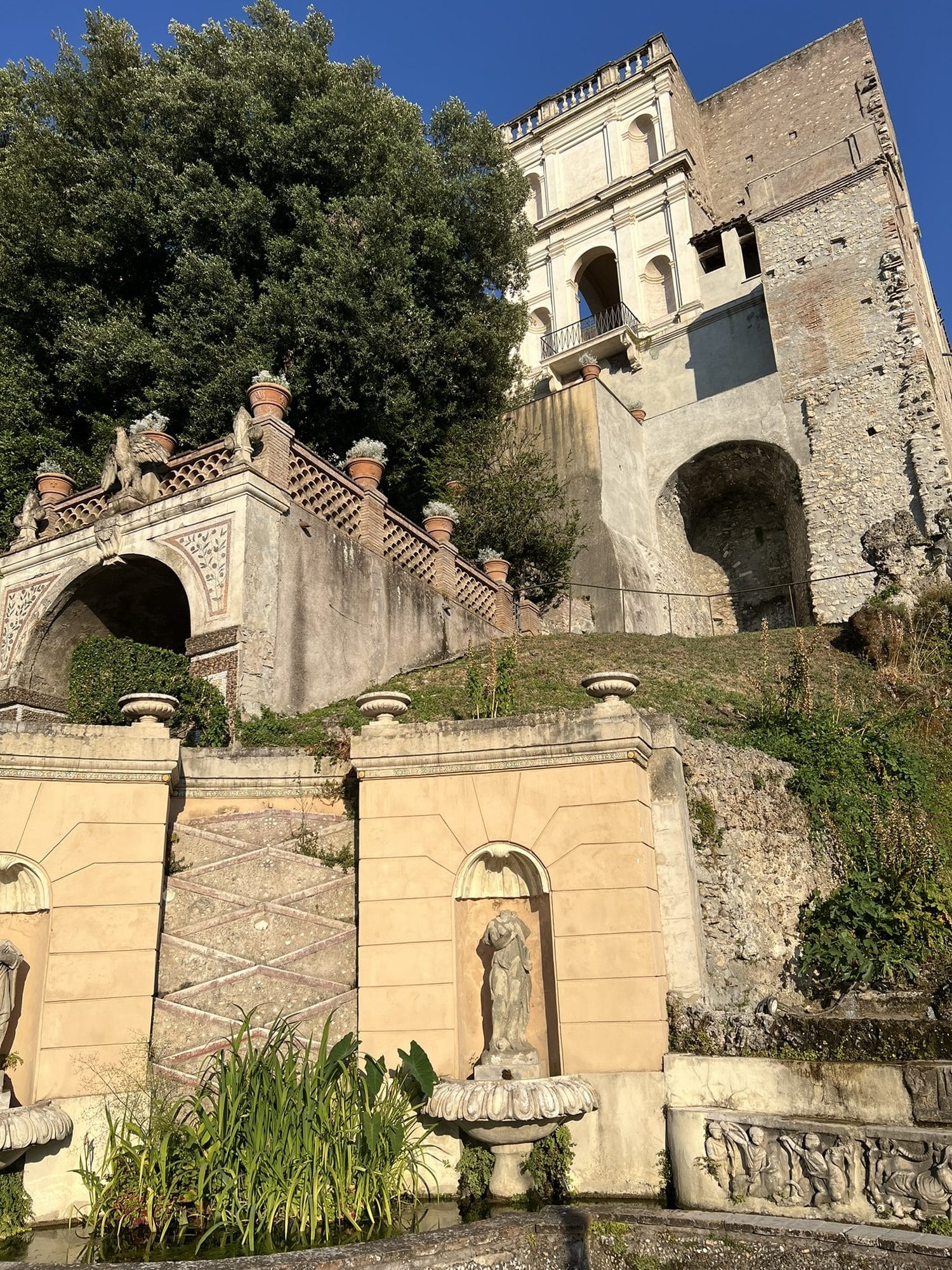 The Rometta fountain with miniature buildings, a staircase and rocks overgrown with vegetation