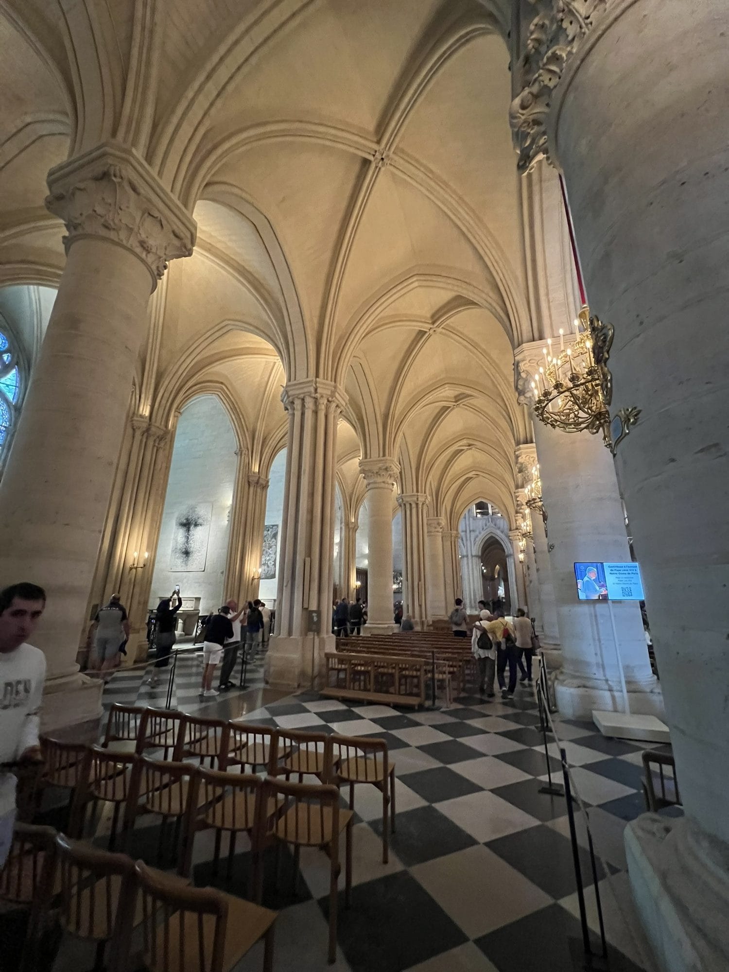 The black and white chequered floor of Notre-Dame between chairs and the piers of a side aisle 