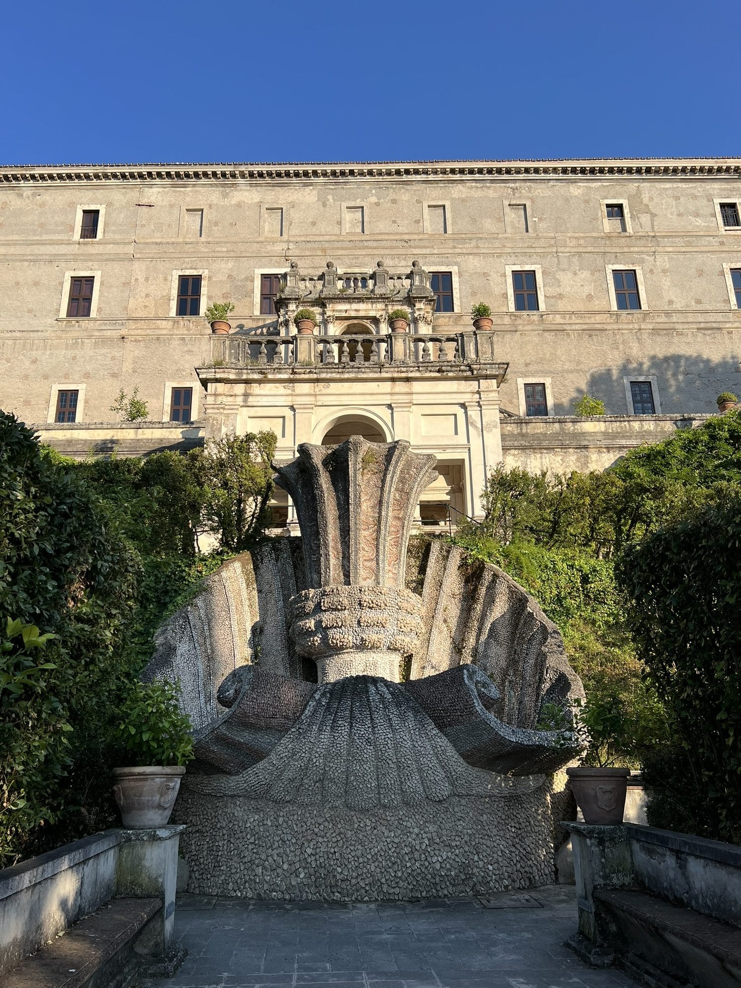 Baroque fountain shaped like a great serrated chalice inside a shell, with the palace façade behind