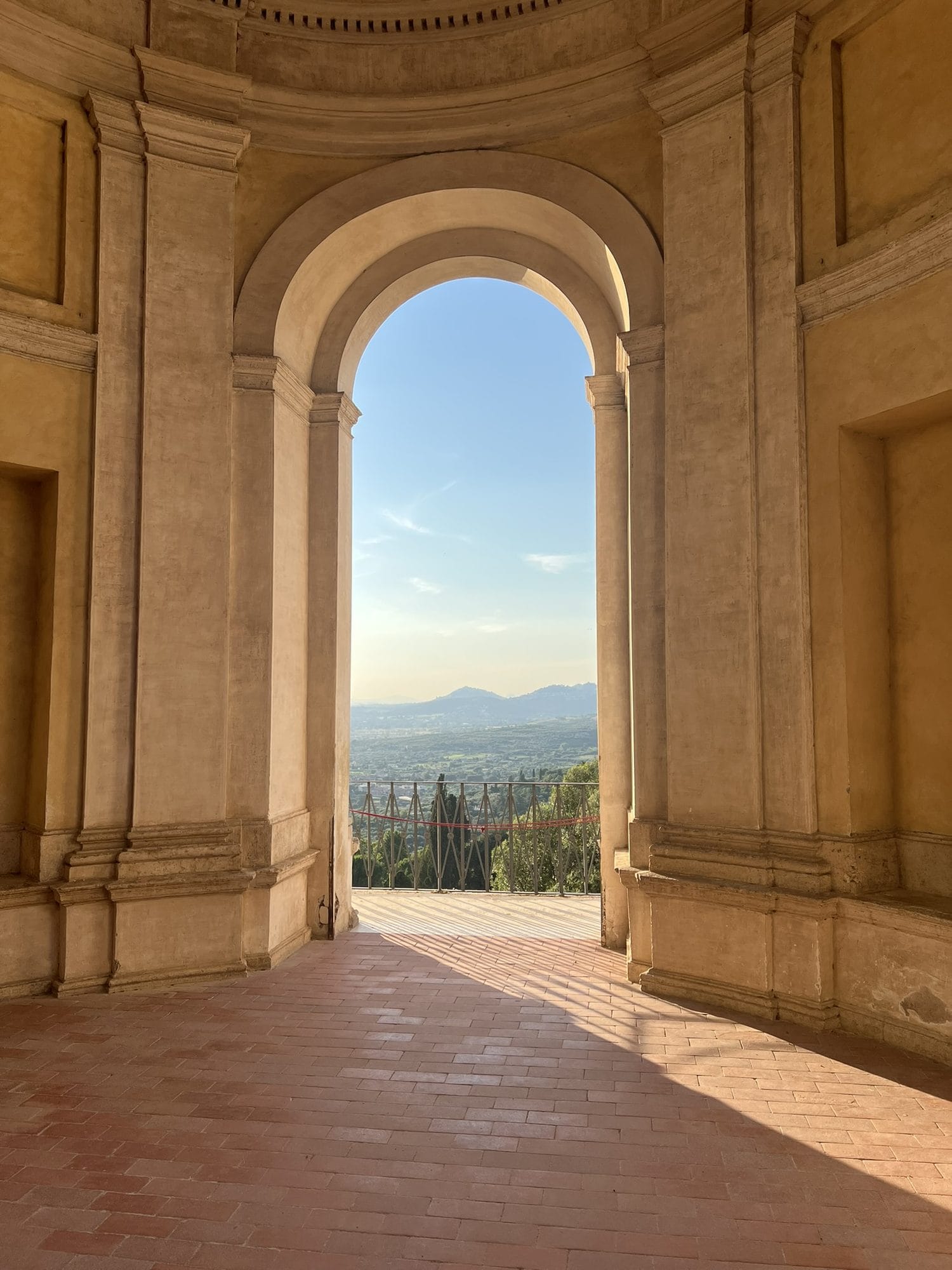 Arch of a loggia framing the countryside and hills in the evening light