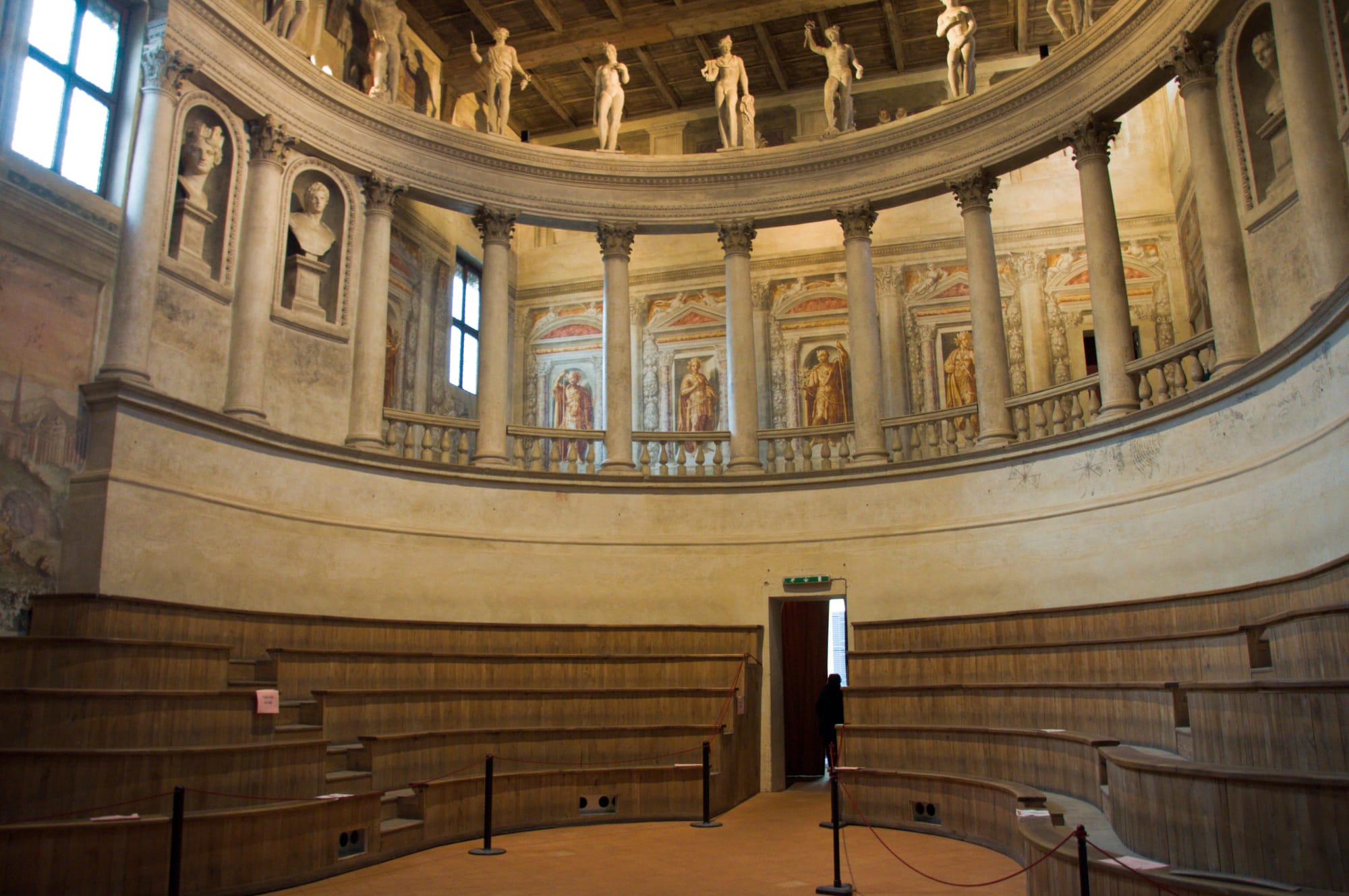 Horseshoe of wooden seating tiers below a curved Corinthian loggia crowned with statues of gods, with frescoed emperors on the wall behind, Teatro all'Antica, Sabbioneta