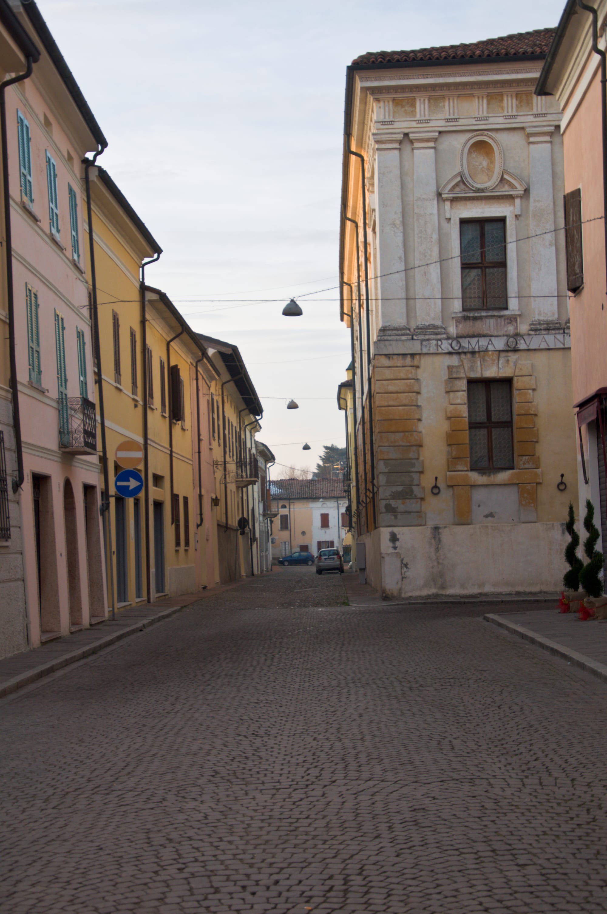 Empty cobbled street in Sabbioneta with pastel houses on the left and the corner of the Teatro all'Antica on the right