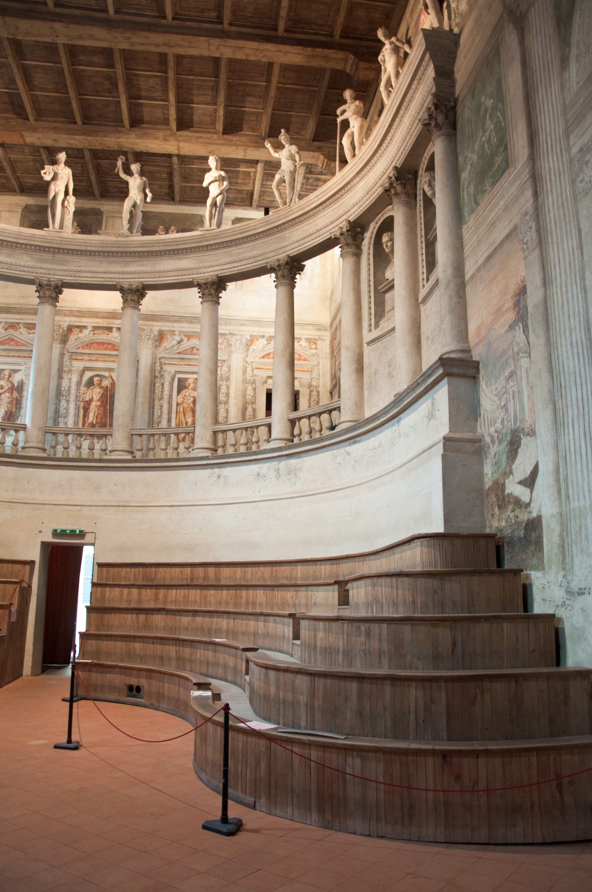 Empty wooden tiers curving up to a colonnade with statues, inside the Teatro all'Antica, Sabbioneta
