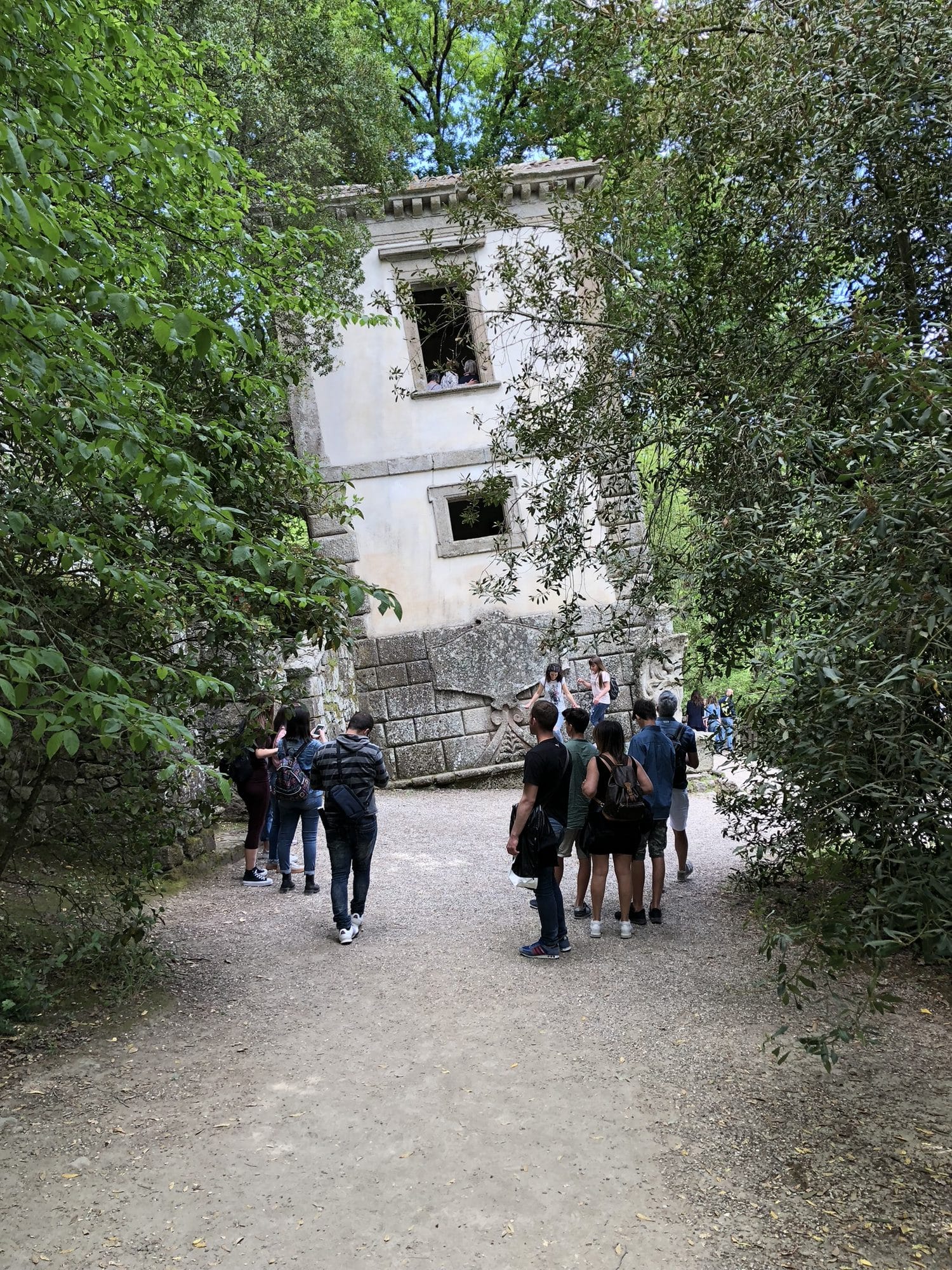 Visitors walking up the tree-lined path towards the small temple at the top of the Monster Park of Bomarzo