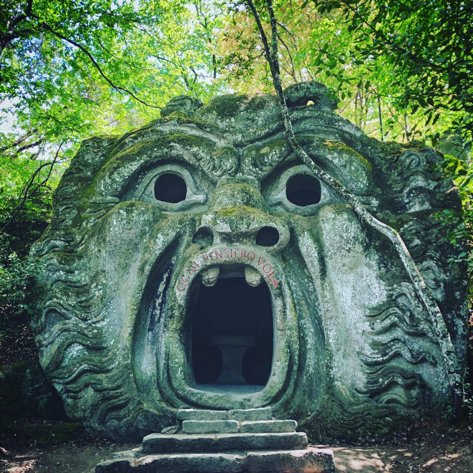 The open mouth of the Orcus in the Sacro Bosco of Bomarzo, half hidden by the trees