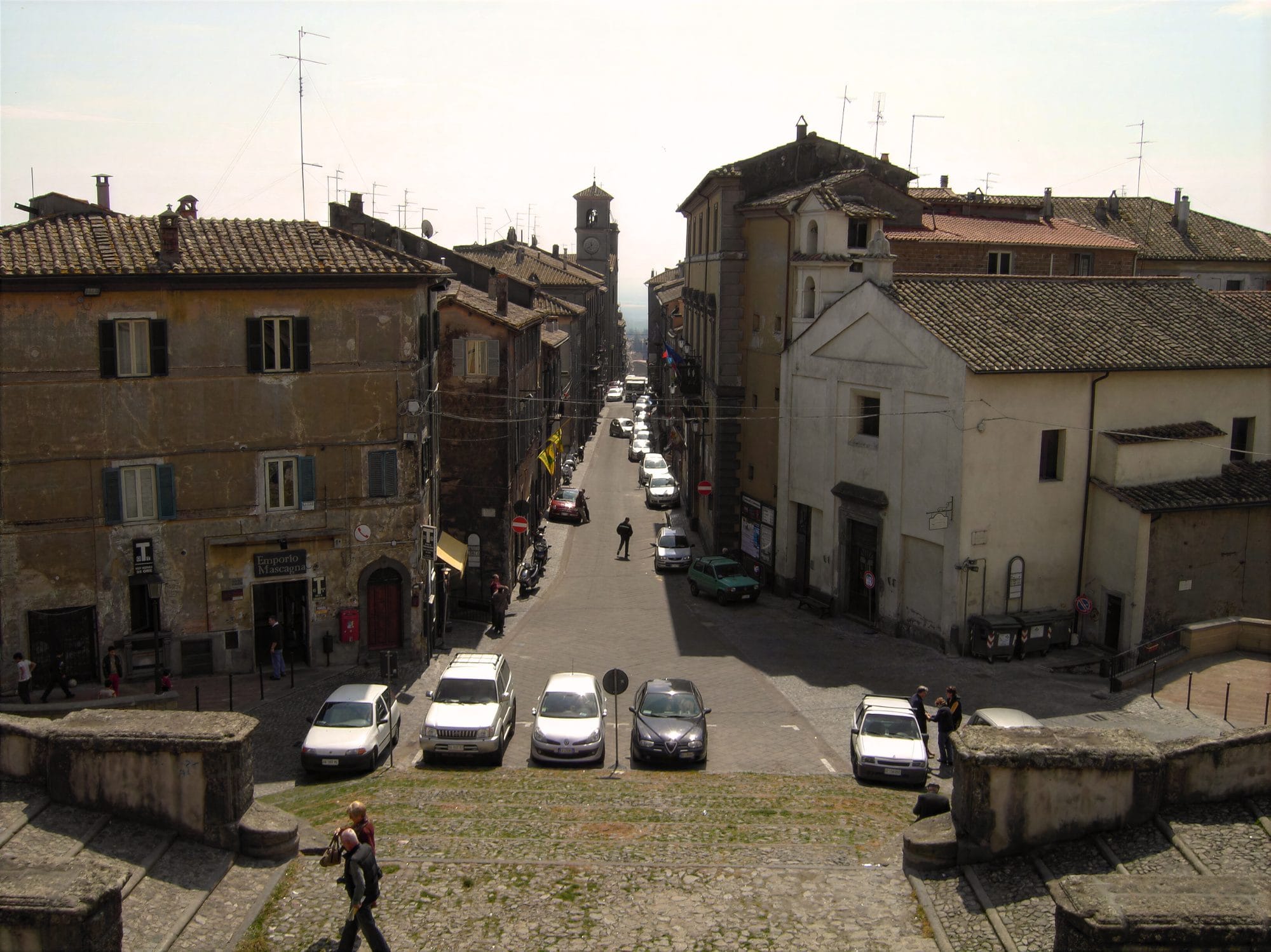View down the straight Via Dritta from the terrace of Villa Farnese at Caprarola, with the rooftops of the town, a tower at the far end and parked cars below