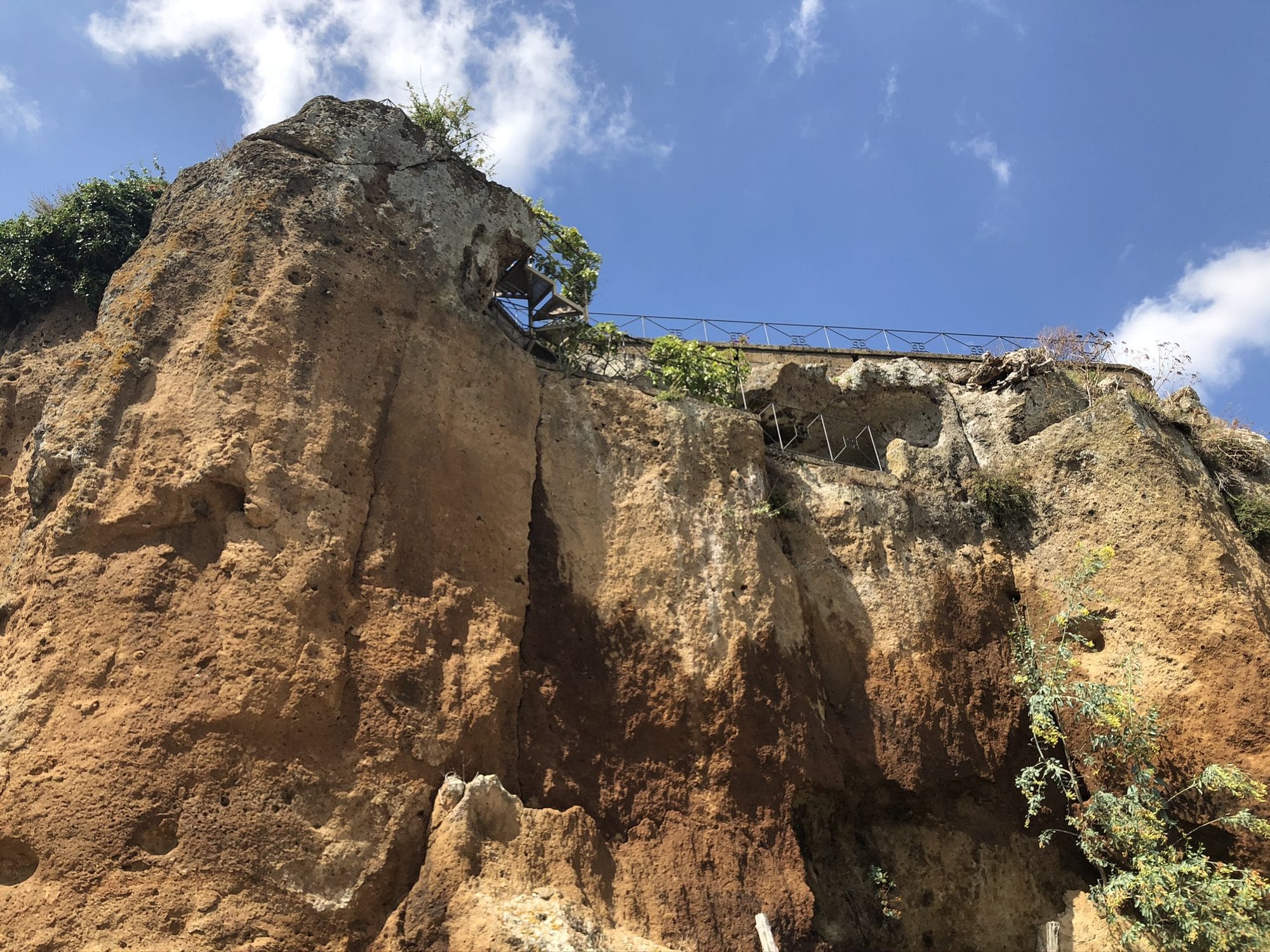 The cracked tufa cliff beneath the edge of Civita di Bagnoregio, seen from the path below