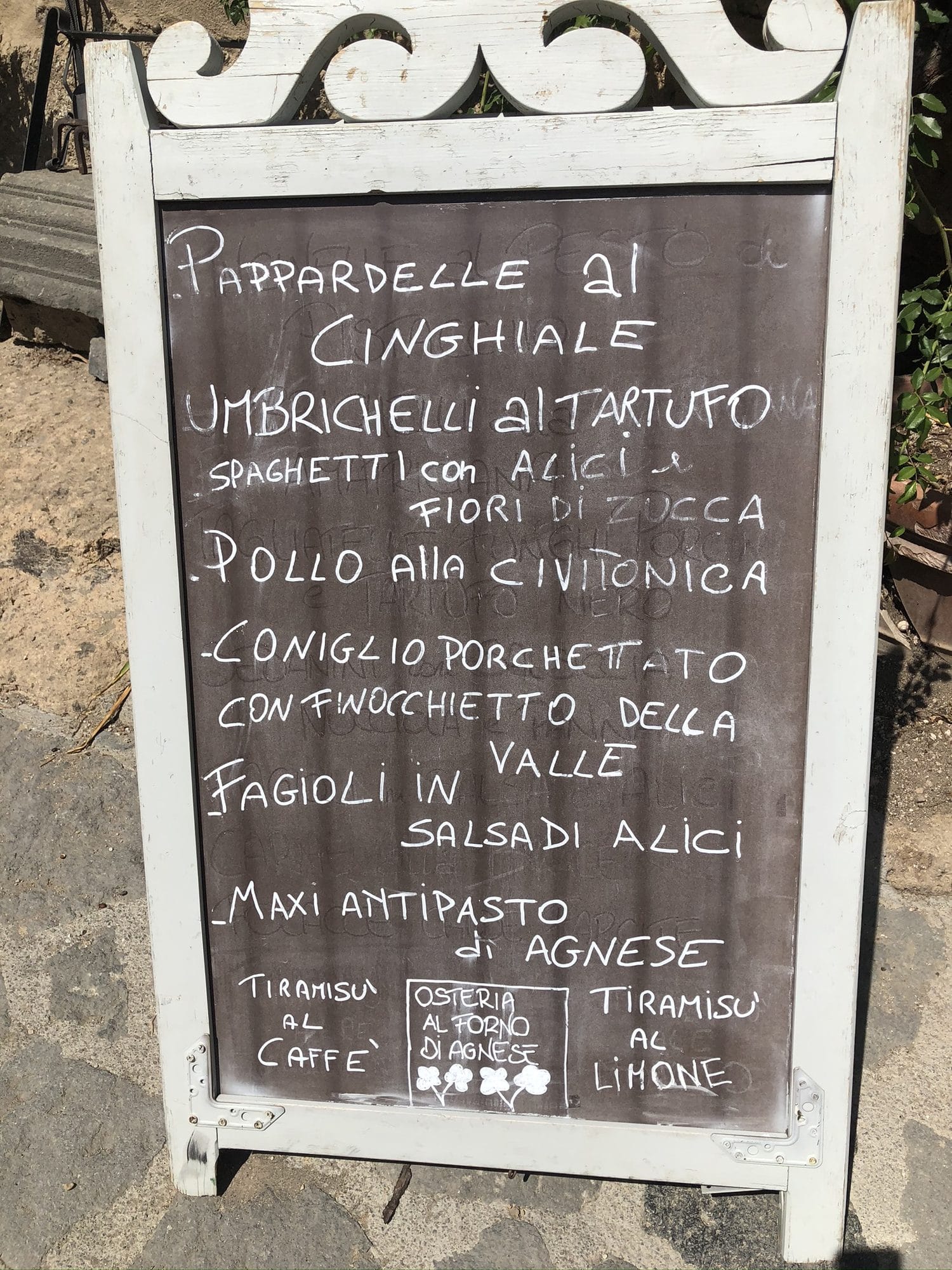 Handwritten chalkboard menu outside an osteria in Civita di Bagnoregio: pappardelle with wild boar, umbrichelli with truffle, porchetta-style rabbit
