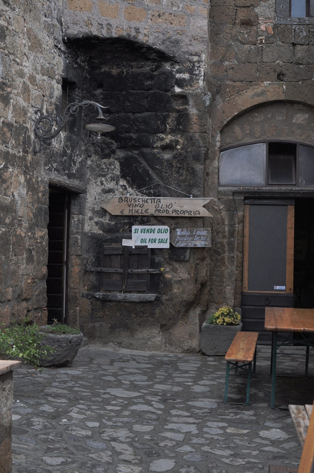 Tufa wall of a house in Civita di Bagnoregio with two blocked arches and a wooden door, the stones left visible