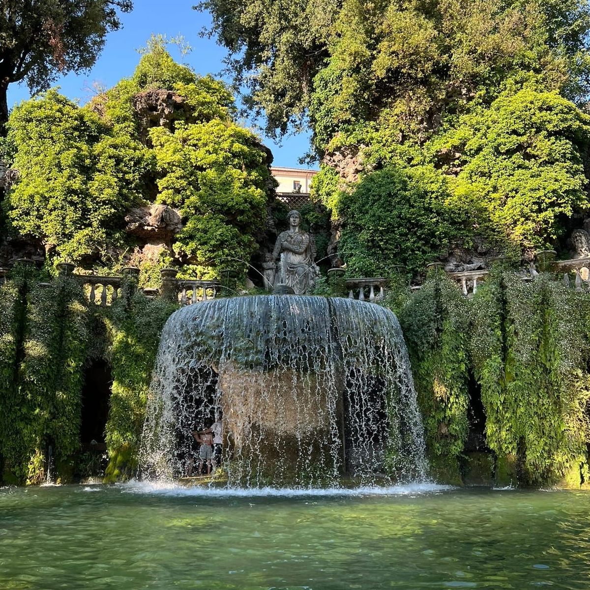 Veil-like cascade falling from a great basin into the oval pool of the Oval Fountain, among climbing plants and balustrades, at Villa d'Este