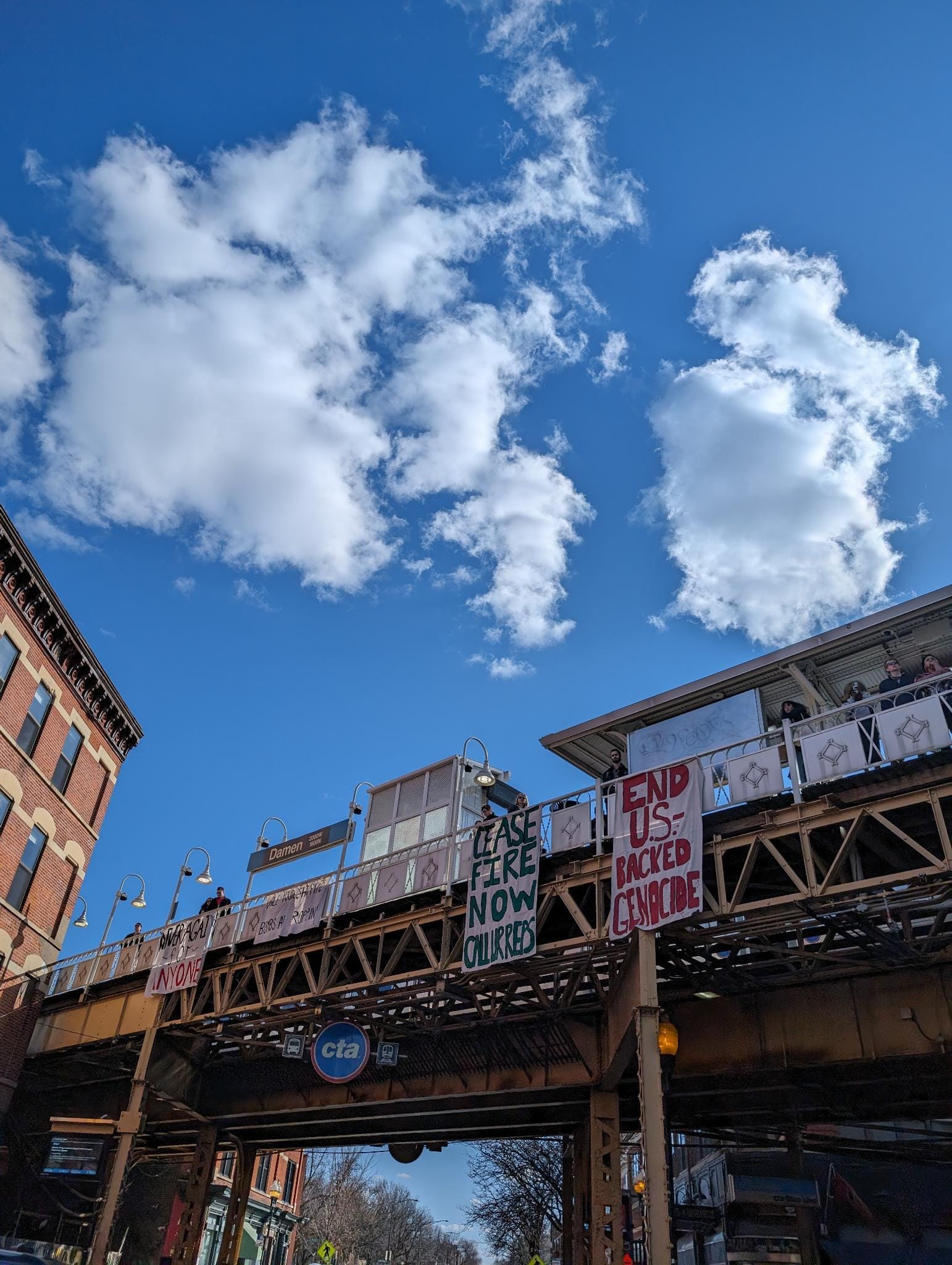 Palestine solidarity protesters hang banners from the Damen el stop in Chicago.