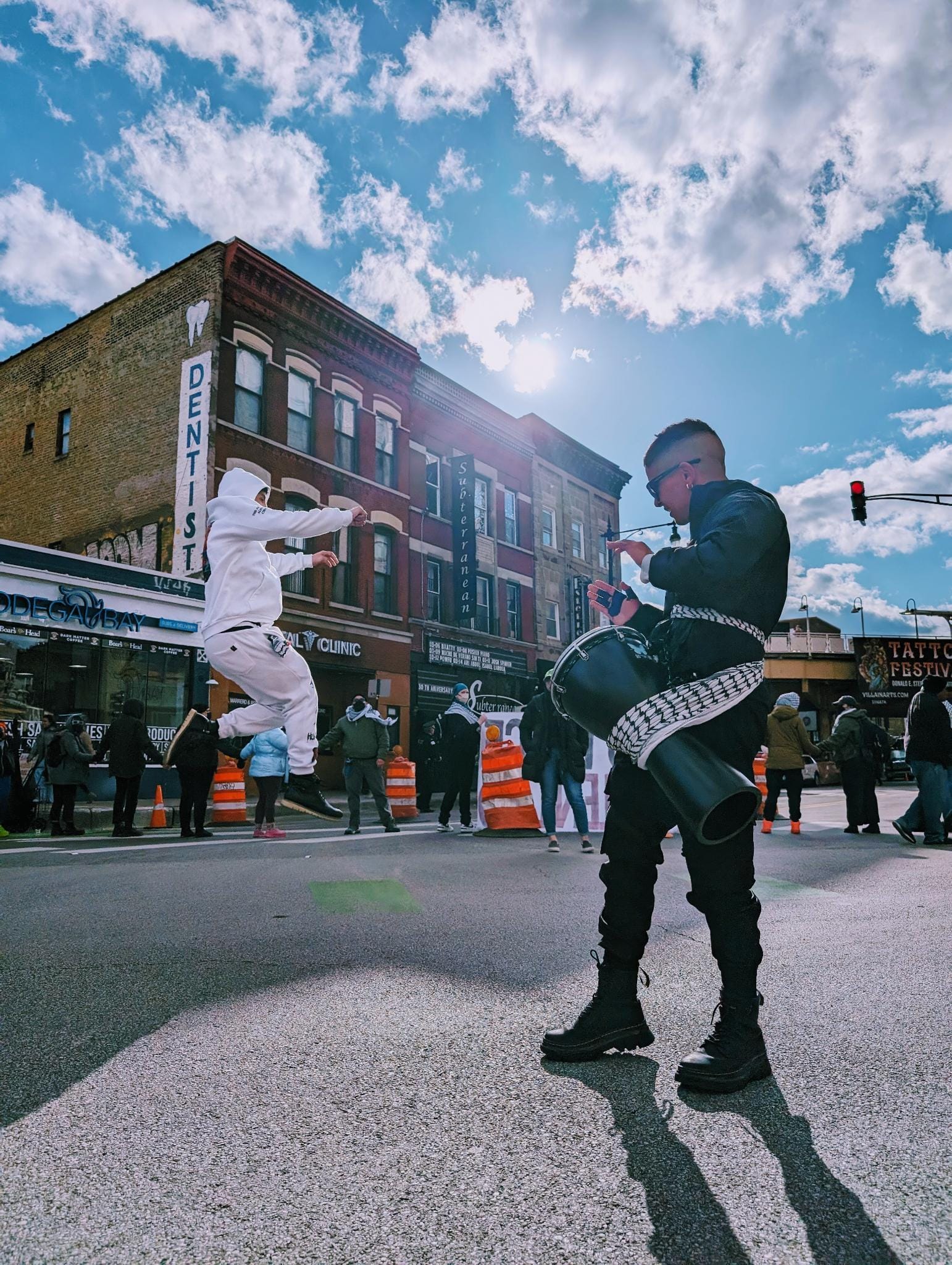A protester drums as another dances in the street during a blockade action.