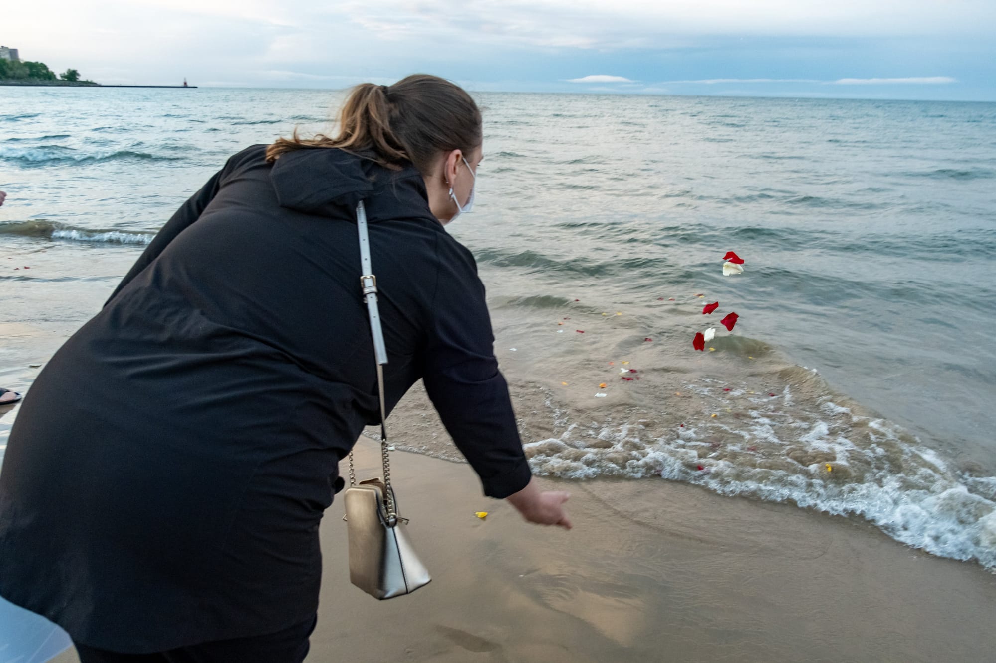 A mourner throws rose petals into Lake Michigan.
