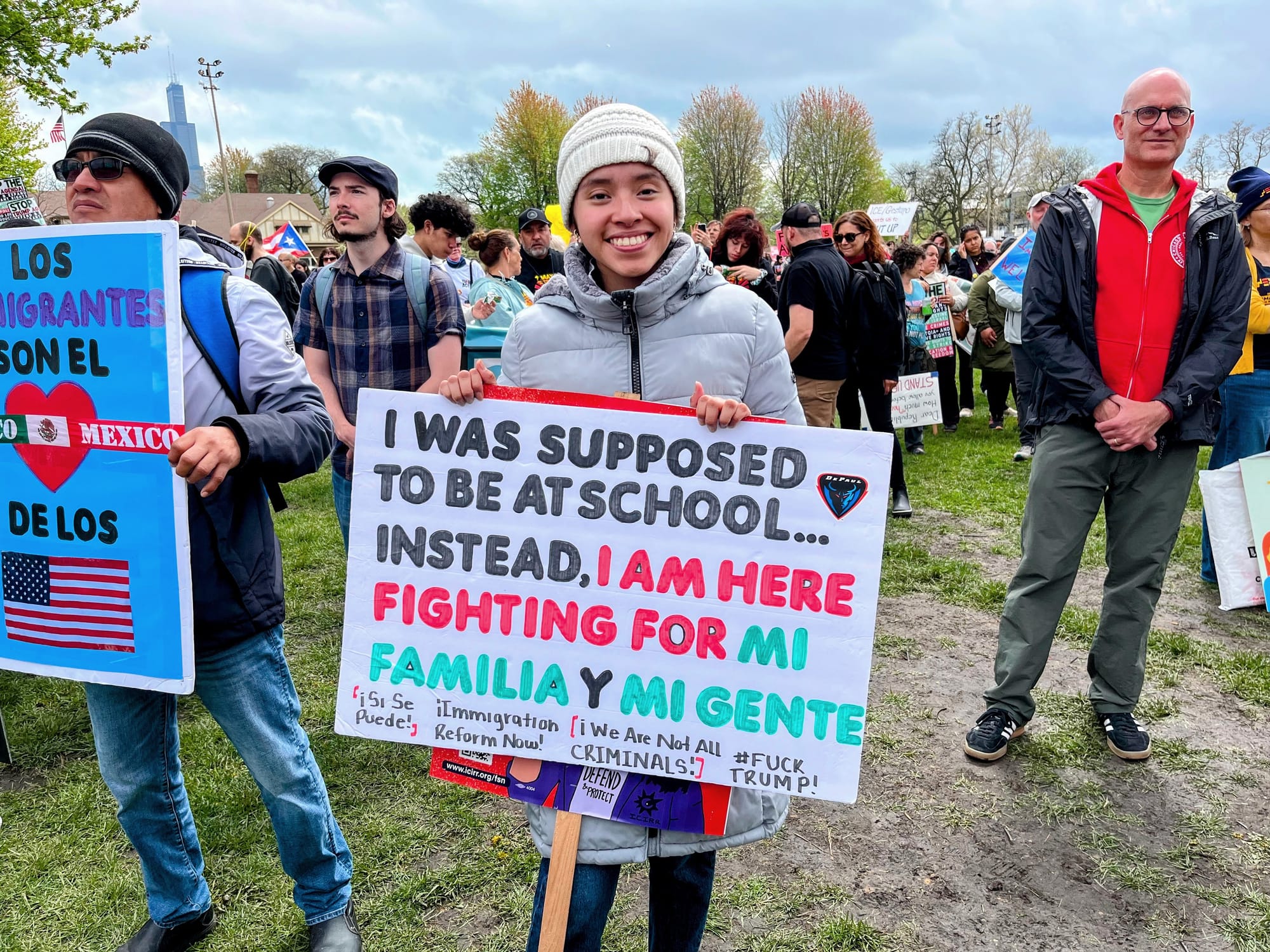 A student carries a sign saying she was supposed to be in school but is fighting for her family.