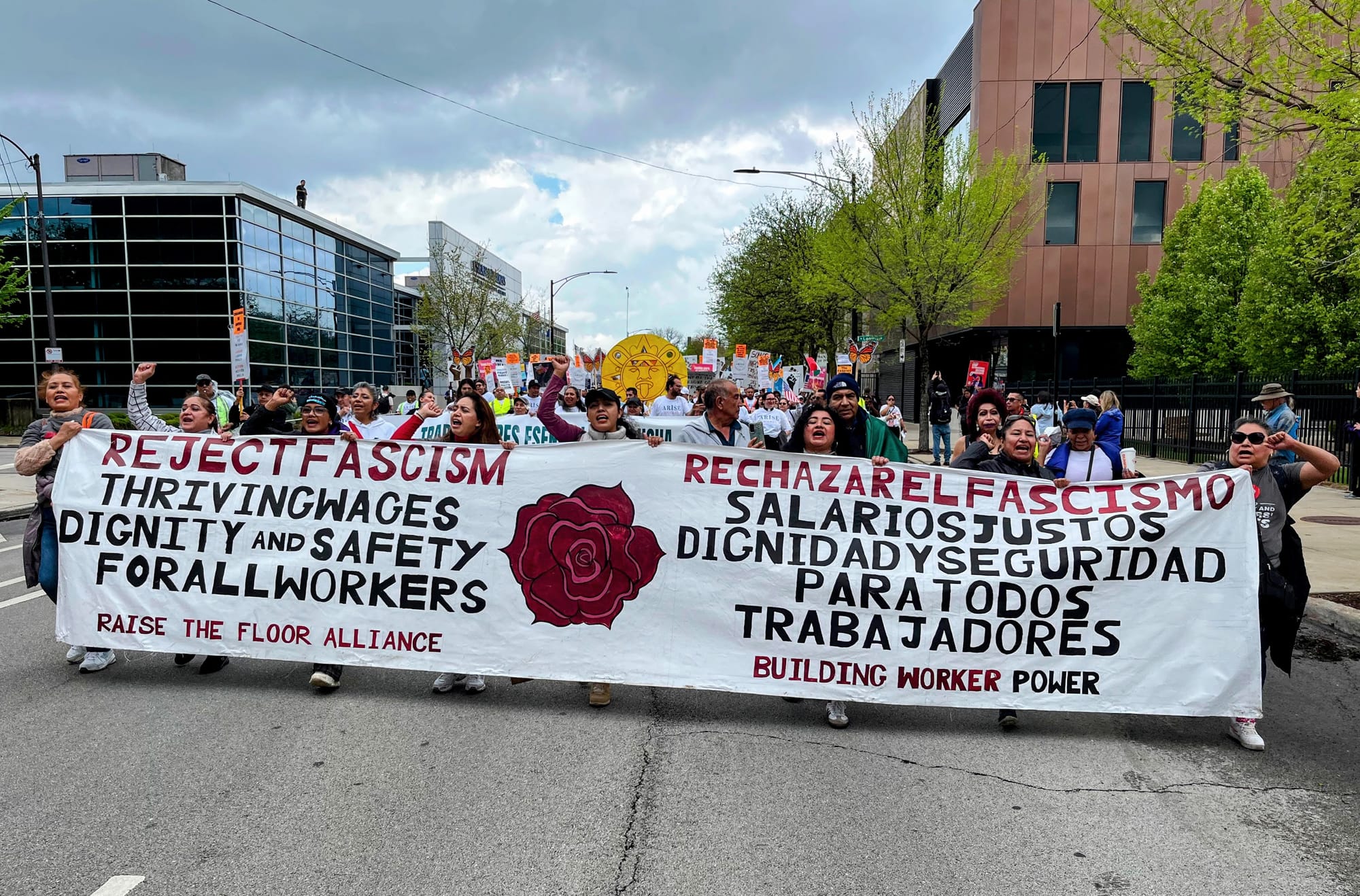 Protesters carry a banner that says "reject fascism" and demands "thriving" wages.