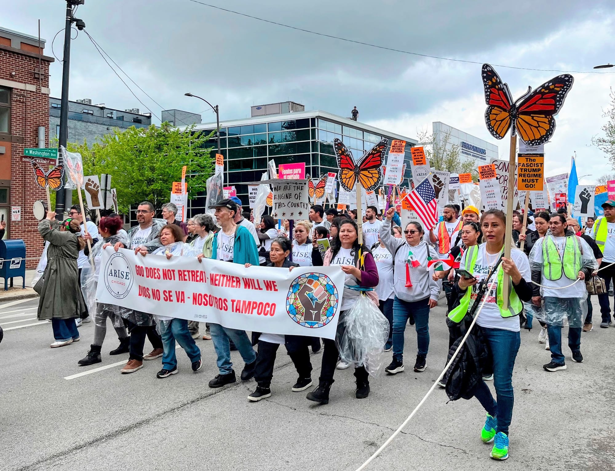 Protesters carry cardboard butterflies and a banner.