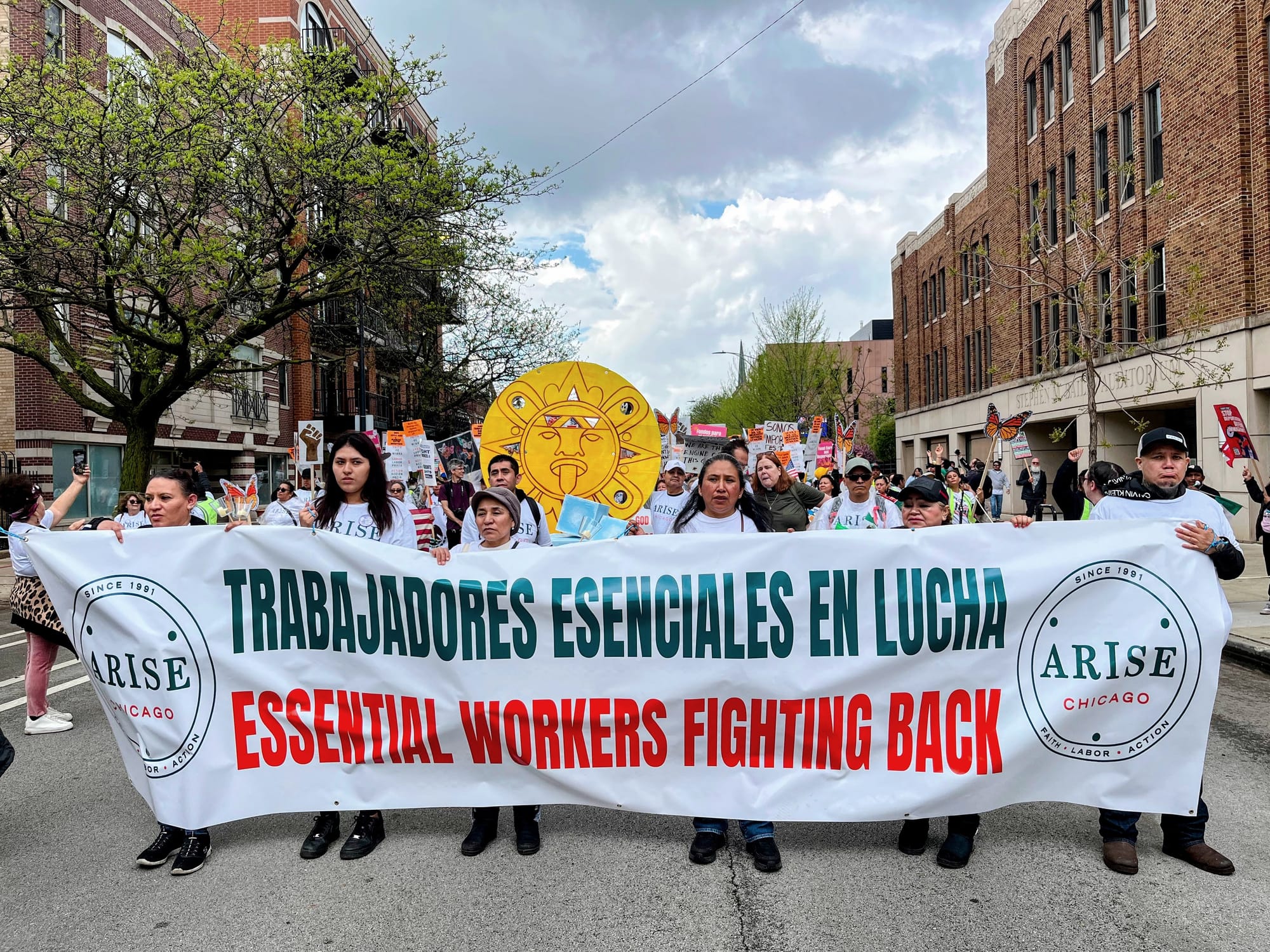 Protesters hold a banner that says "essential workers fighting back."