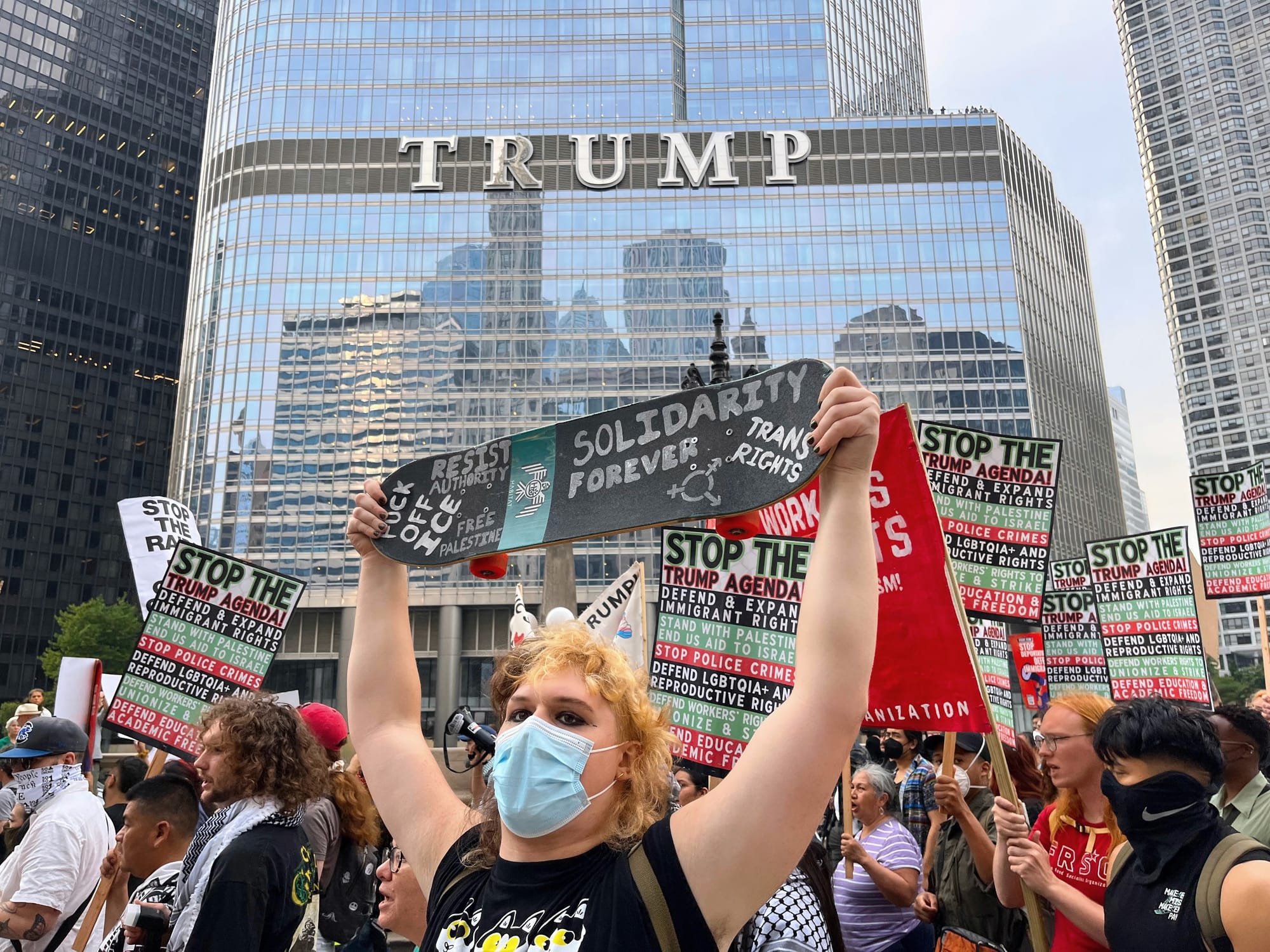 A protester holds a skateboard with the words "solidarity forever" written on it.