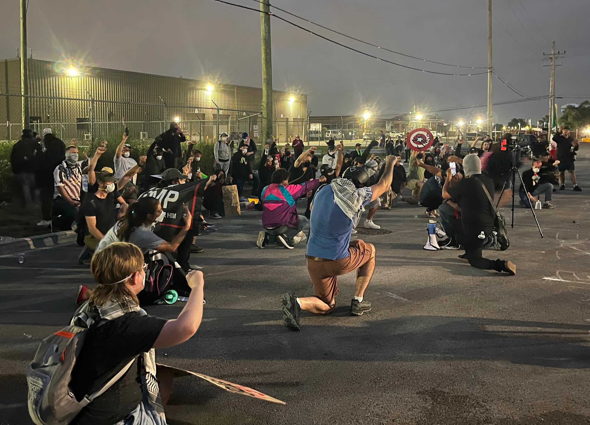 Protesters kneel in the street with their fists in the air.