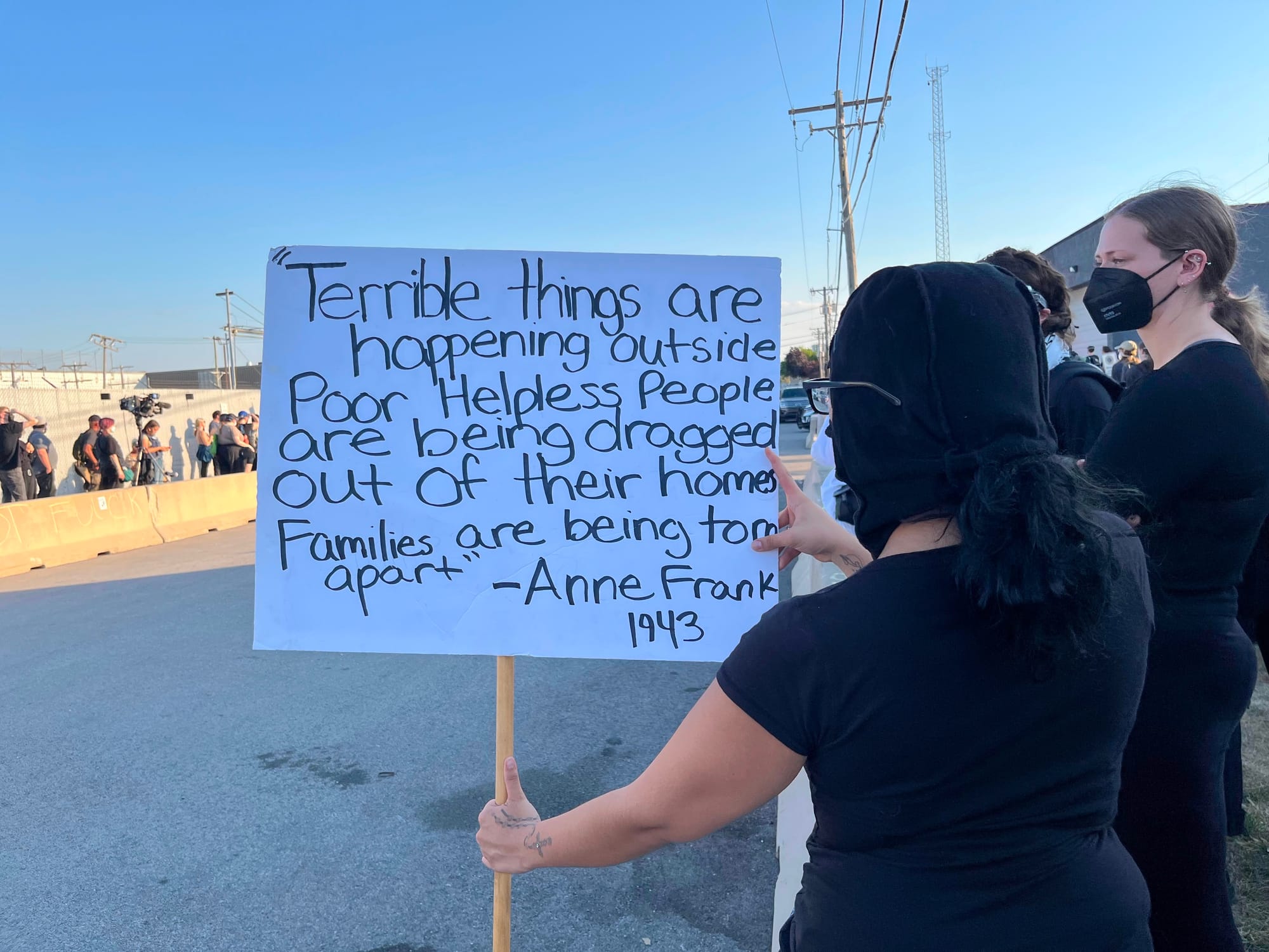 A woman holds a sign quoting Anne Frank at a protest outside an ICE facility.
