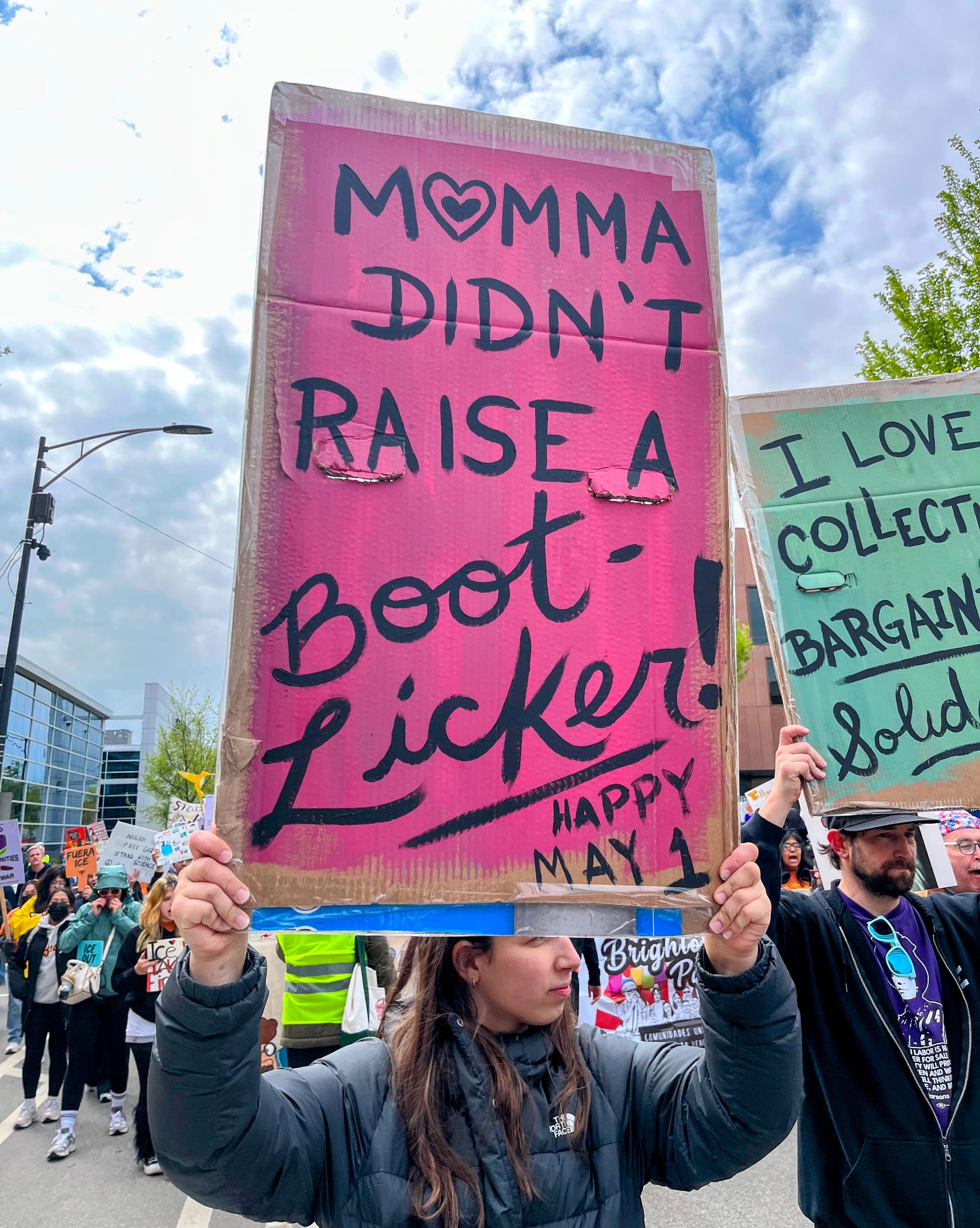 A protester holds a sign that reads, "Momma didn't raise no bootlicker."