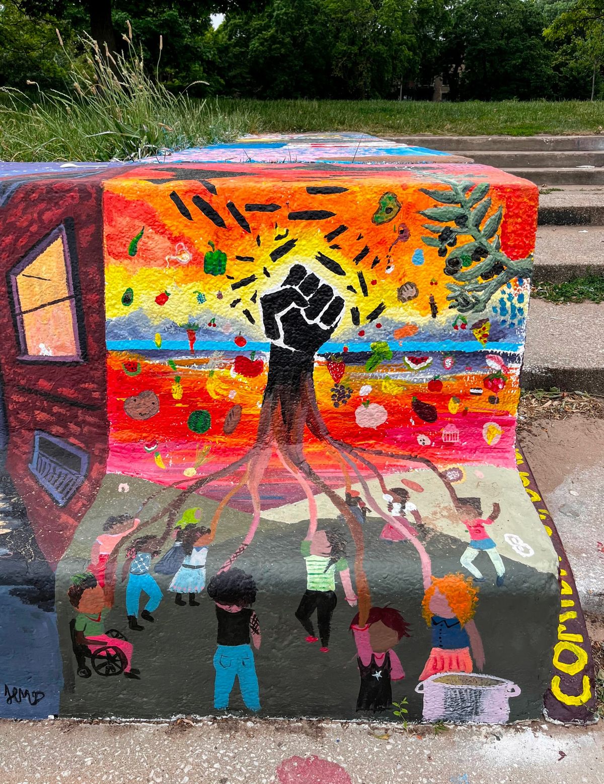 A mural depicts the arms of community members as the roots of a tree. The tree's body is a power fist.