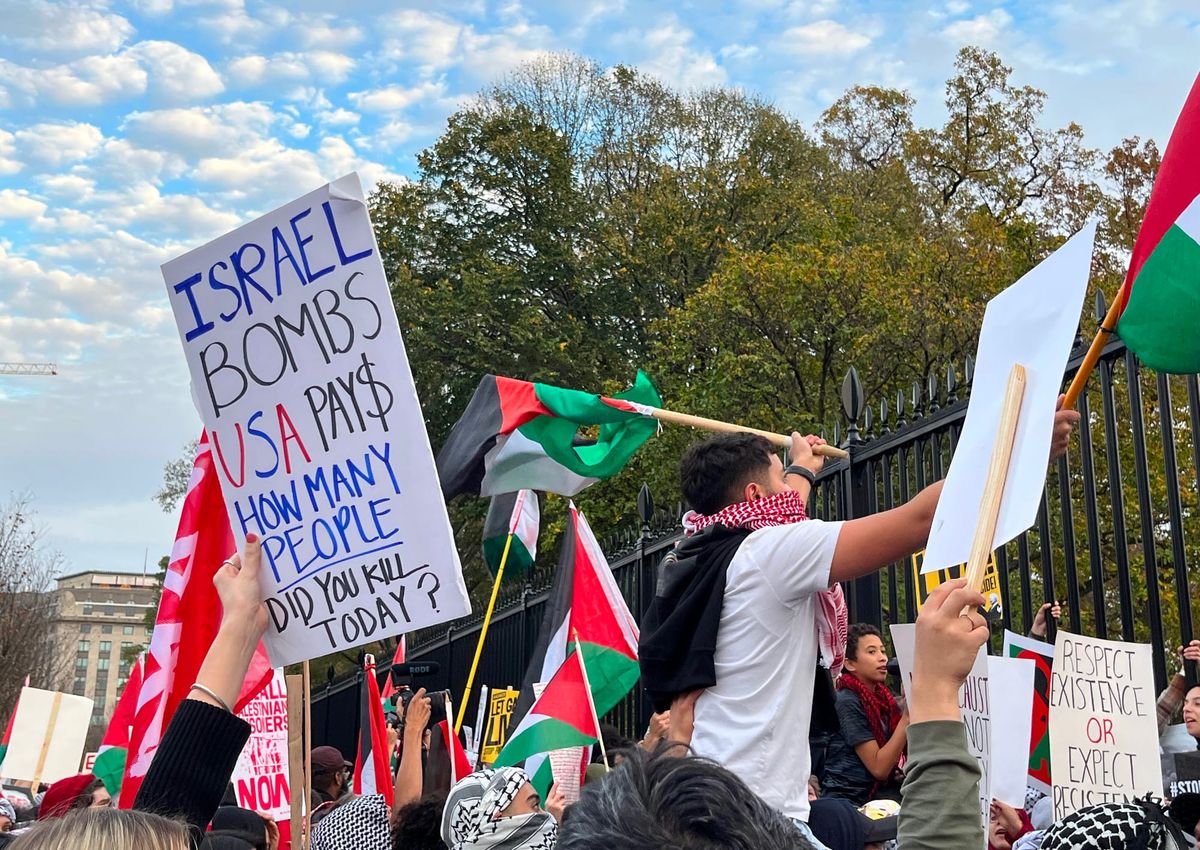 A crowd of protesters at the White House gates. One sign reads, "Israel Bombs, US Pays."