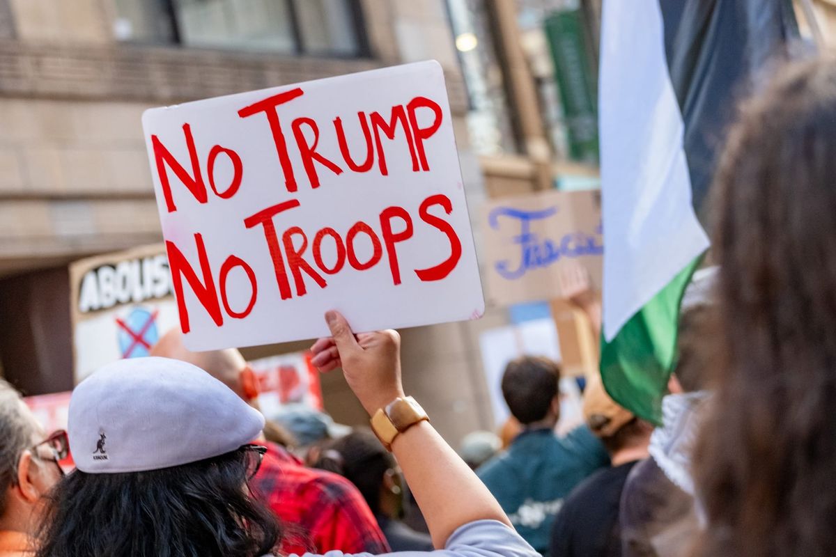 A protester holds a sign that reads, "No Trump, No Troops."