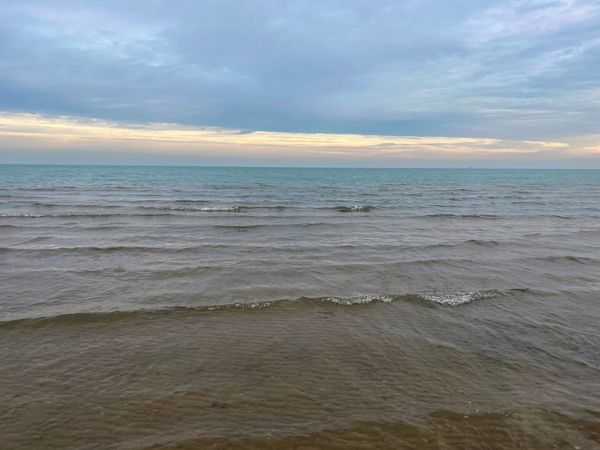 Waves roll gently onto a Lake Michigan beach in Chicago. The sky is overcast.