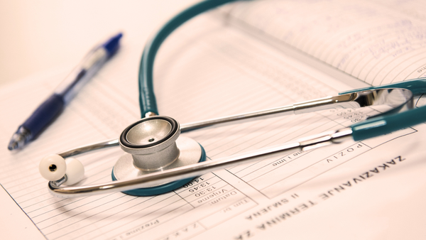 A stethoscope and a pen lay on a patient's chart.