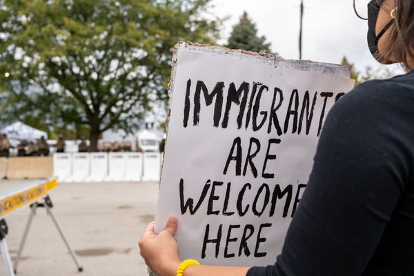 A protester holds a sign that says, "Immigrants are welcome here."