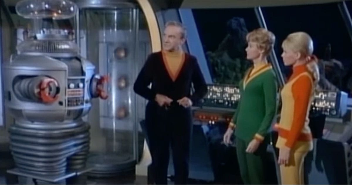 Image of Robot standing with Dr. Smith, Mrs. Robinson, and Judy Robinson on the space ship.