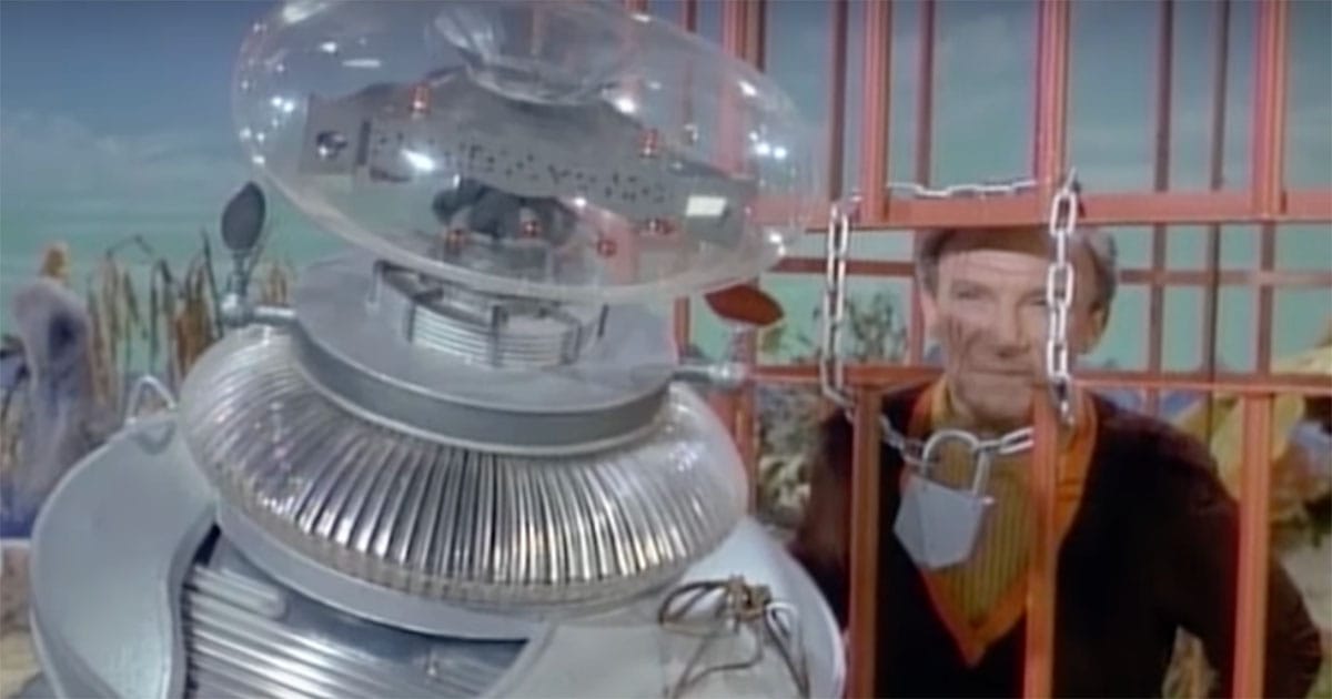 Image of Dr. Smith in a cage being watched by Robot.