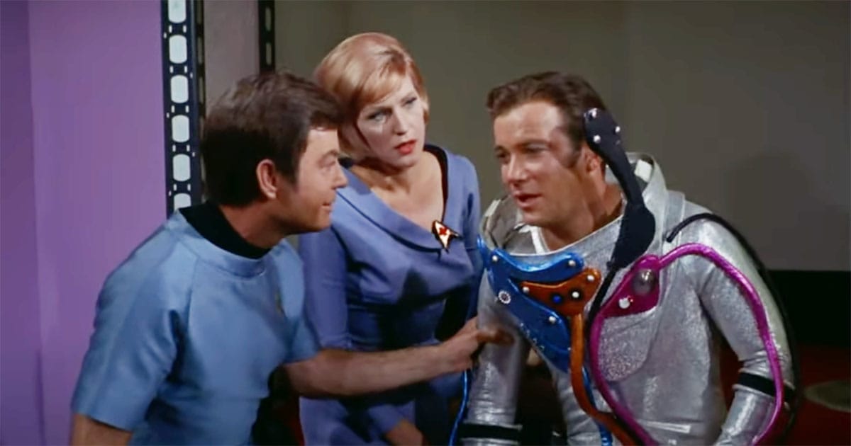 Captain Kirk in silver space suit with Dr. McCoy and nurse in "Star Trek."
