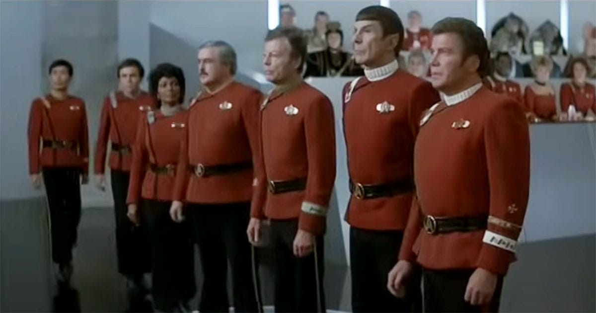 Kirk and crew in red Starfleet uniforms standing in tribunal scene from "Star Trek III"