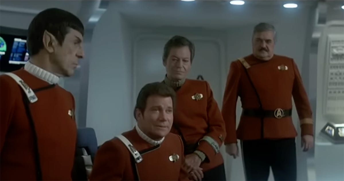 Kirk, Spock, McCoy, and Scotty in red uniforms on the bridge of the Enterprise in later-era "Star Trek" film.