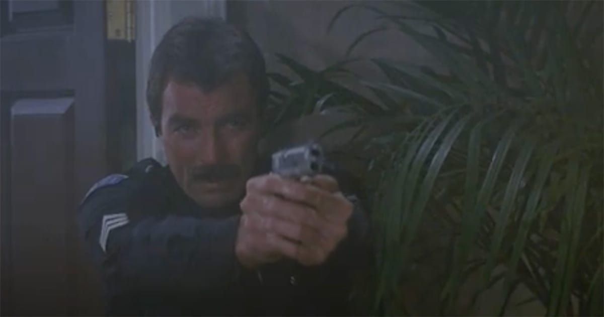 Tom Selleck as Sergeant Ramsay aiming a pistol from behind a door and palm plant in a smoky scene from "Runaway."