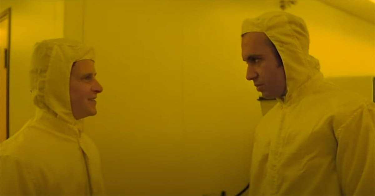 Two men in yellow cleanroom suits share a tense moment inside a futuristic lab in "Runaway."