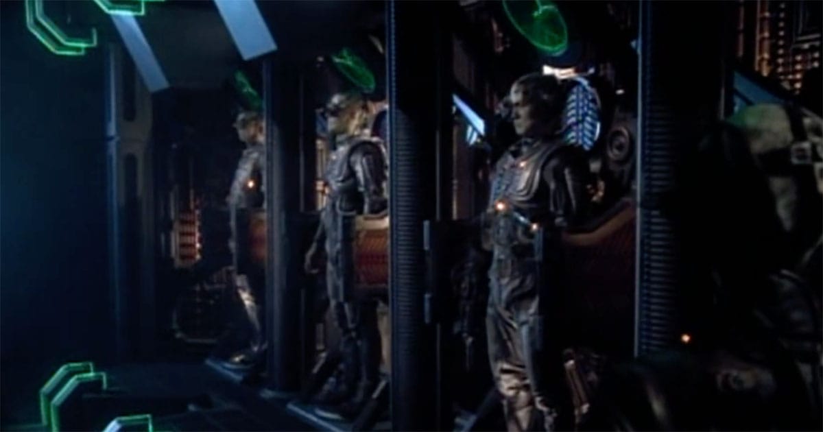 Several Borg drones standing in alcoves aboard a Borg ship, preparing to continue their mission of assimilation.