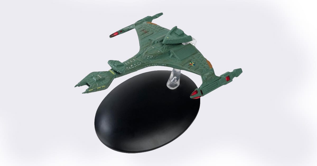 Green die-cast model of the Klingon V'orcha Class starship from "Star Trek," displayed on a black stand with red and yellow accents.