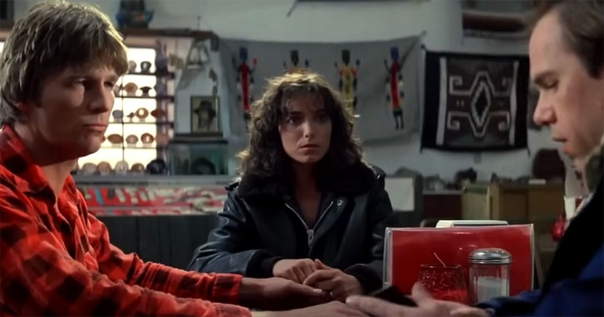 Scene from "Starman" showing Jeff Bridges, Karen Allen, and Charles Martin Smith seated around a table in a small shop, symbolizing intimate dialogue beyond institutional interference.