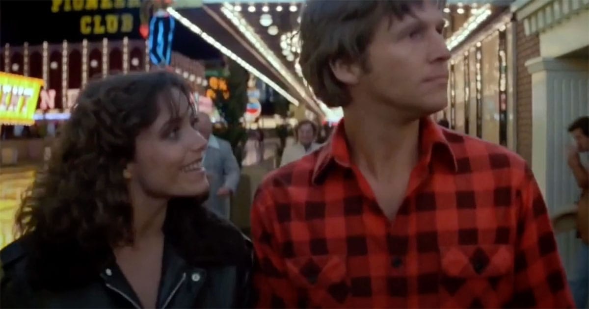 Scene from "Starman" with Jeff Bridges and Karen Allen walking under bright lights in a crowded entertainment district, reflecting the tension between personal connection and public chaos