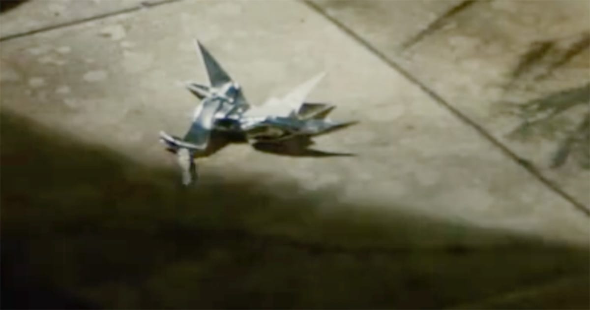 Origami unicorn lying on a dimly lit floor, surrounded by shadows and soft light in an empty room