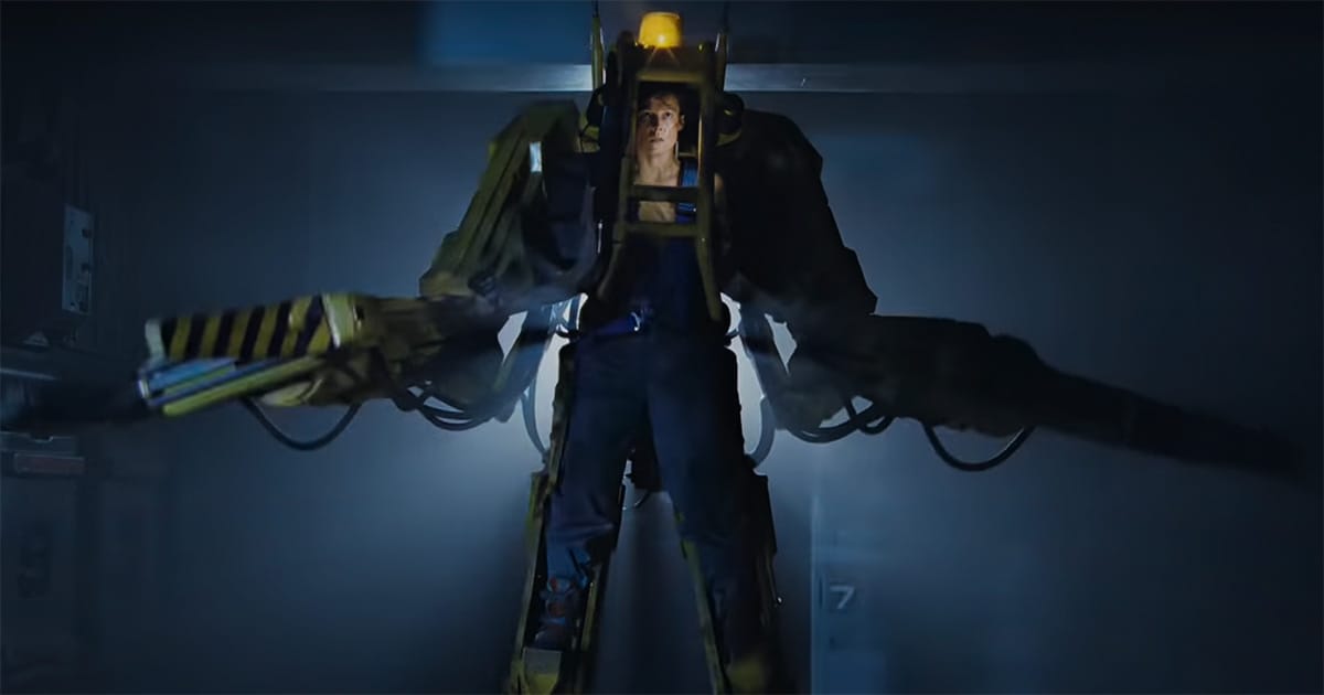 Ripley in power loader suit in Aliens 1986 standing in shadow with arms extended before final battle.