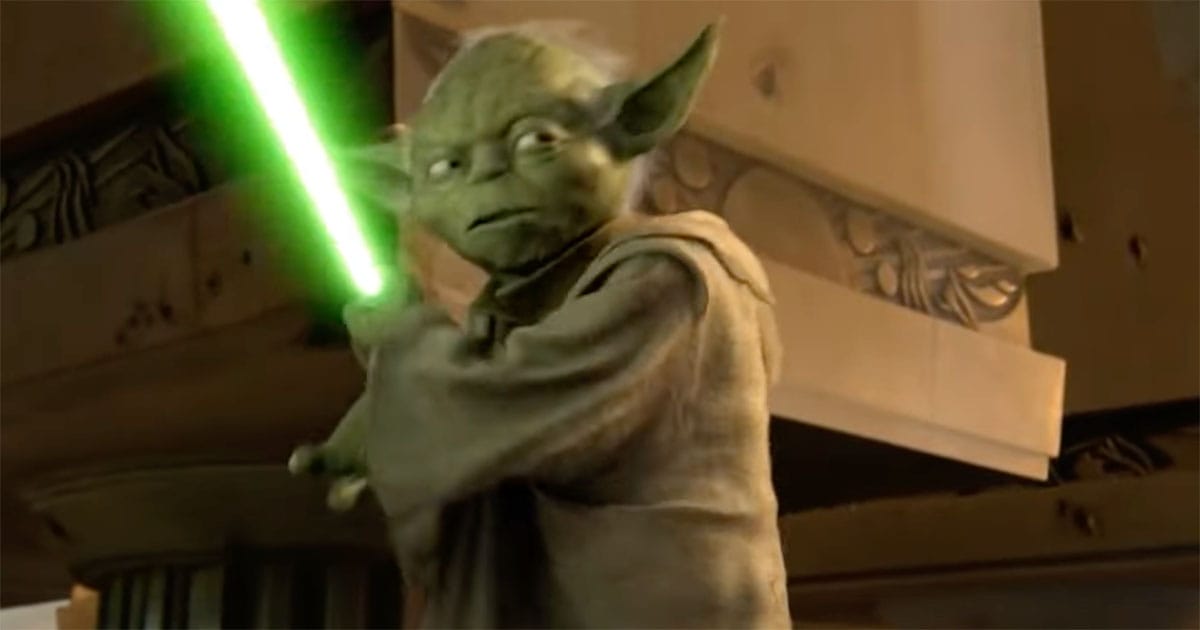 Yoda holding a green lightsaber, standing alert in a dim stone chamber during the aftermath of Order 66 in "Revenge of the Sith"