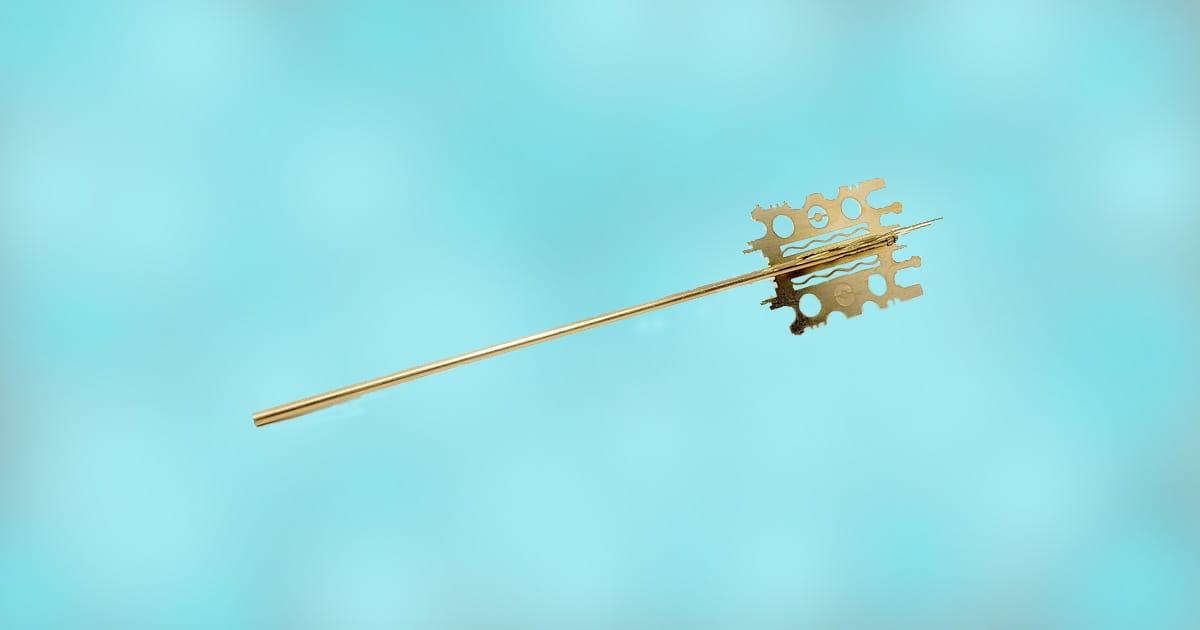 Gold replica of the Mondoshawan Tomb Key from The Fifth Element shown against a light blue background