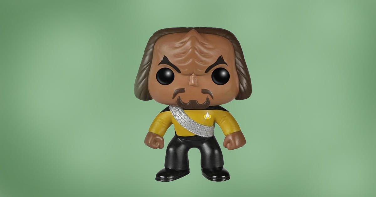 Funko Pop figure of Worf from Star Trek: The Next Generation wearing a yellow Starfleet uniform with sash, against green background