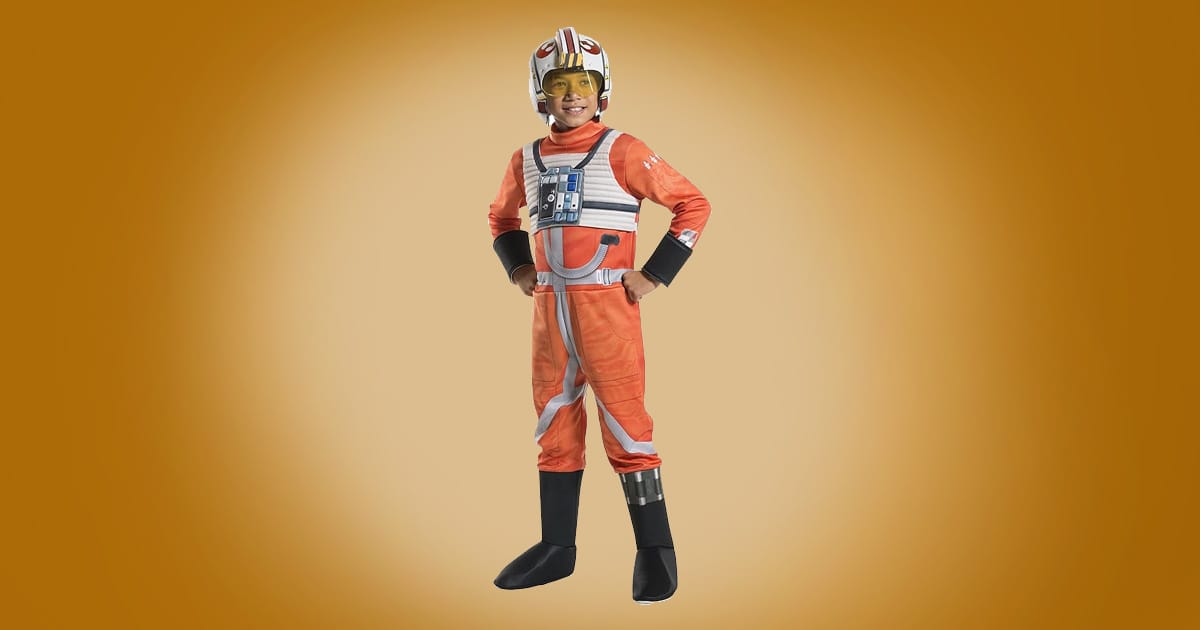 Child X-Wing pilot Star Wars costume with orange jumpsuit, chest gear, and white helmet with yellow visor on orange background.