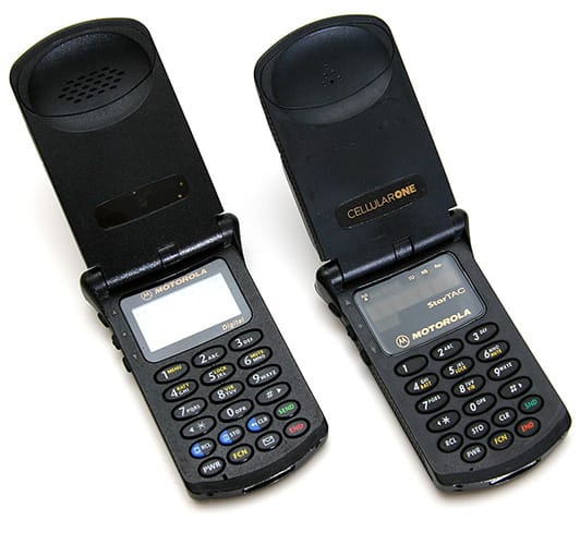 Two open Motorola StarTAC flip phones from the 1990s, the first widely popular mobile phones inspired by the Star Trek communicator.