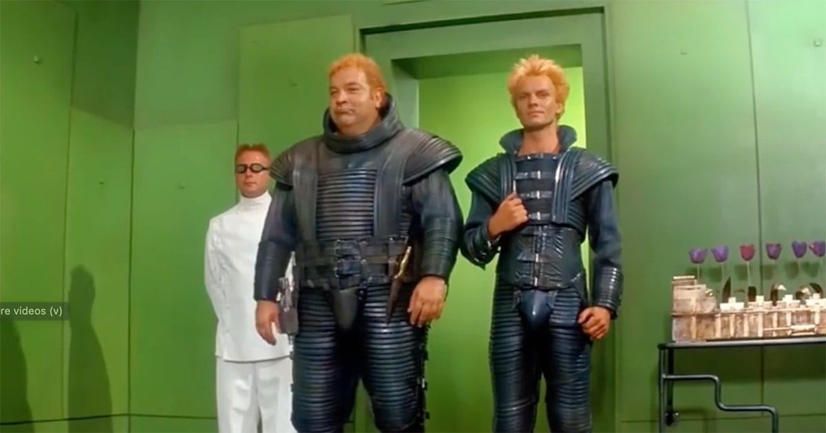 Rabban and Feyd-Rautha stand before a green Harkonnen chamber with a guard in the background